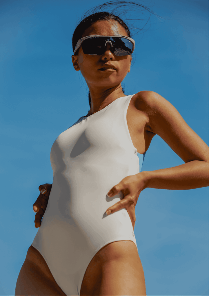 woman waist-deep in seawater smiling confidently at the camera, her Leda Sport one-piece perfectly highlighting its butt-lifting and sculpting cut.