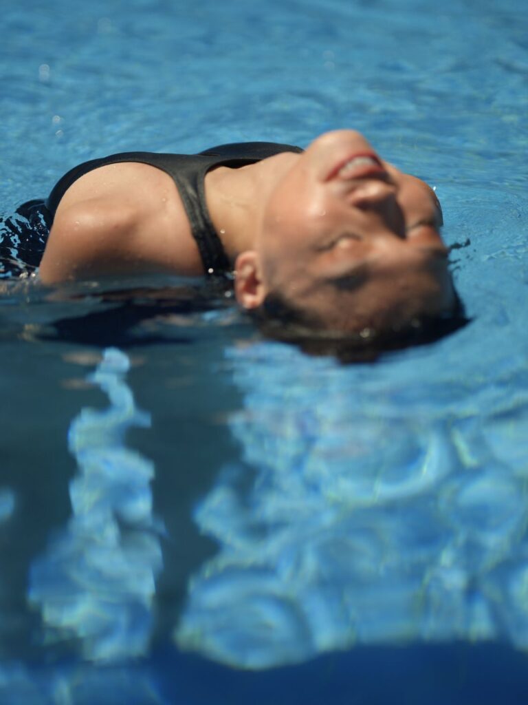Woman floating in a pool in the black Gene one-piece