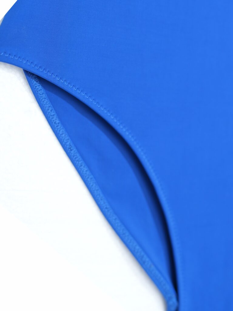 Flat-lay close-up of the herringbone binding around the armhole of the royal blue Gene one-piece