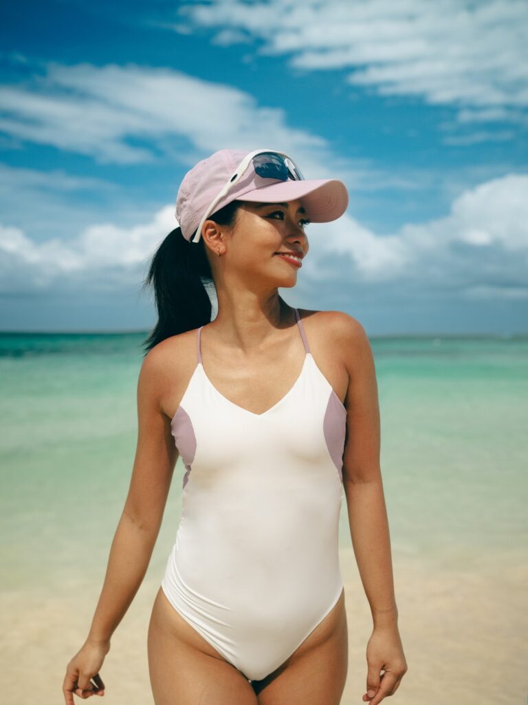 Woman on a tropical beach in the cream white Pura V-neck one-piece with lilac side panels