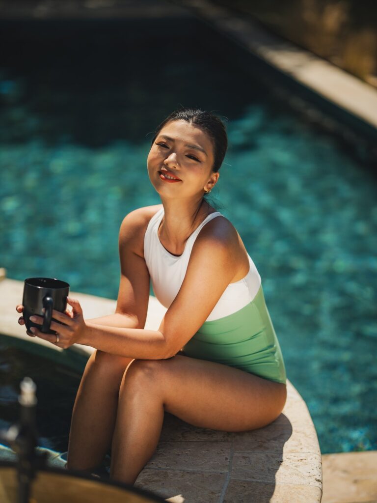 Woman sitting at the edge of a pool in the Mira one-piece