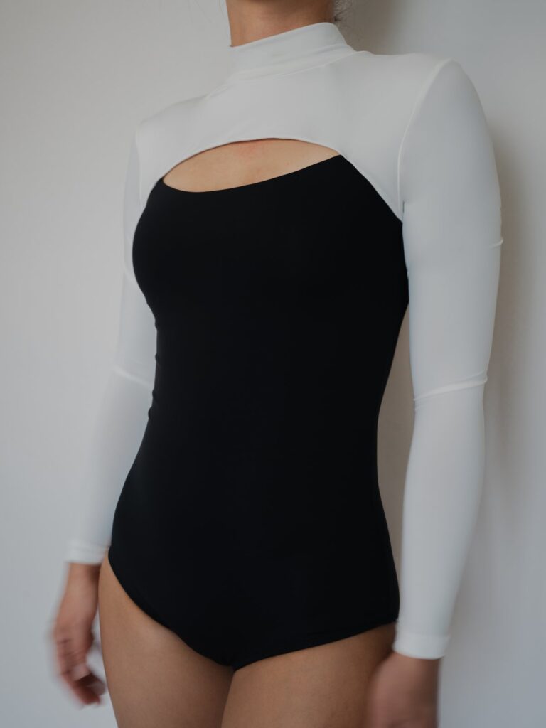 Close-up of the black body and white long sleeves of the Rosa one-piece