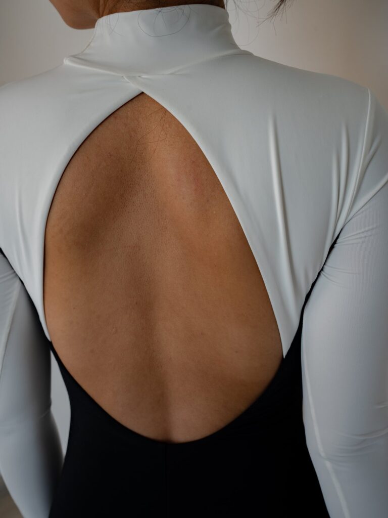 Close-up of the deep U open back of the Rosa one-piece with white sleeves