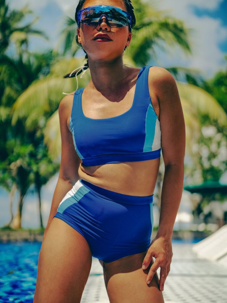 Woman in sunglasses under palm trees in the royal blue Zeta two-piece