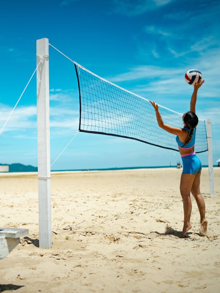 Woman playing beach volleyball in the azure blue Tenacy two-piece