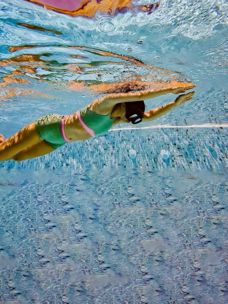 Woman swimming under water in the matcha green Tenacy two-piece