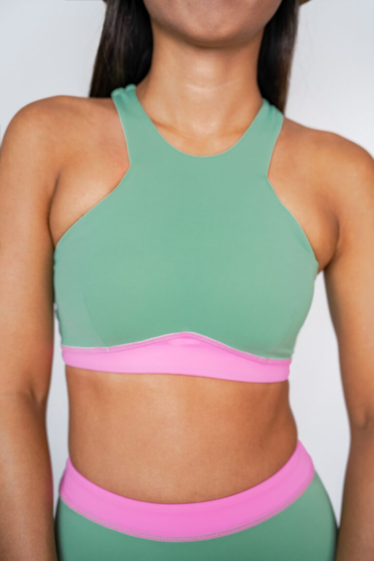 Close-up of the Tenacy two-piece top in matcha green with a high neck and pink underband