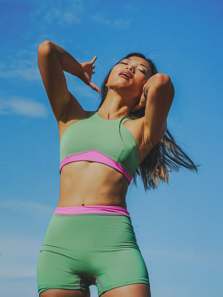 Woman against a blue sky in the matcha green Tenacy two-piece