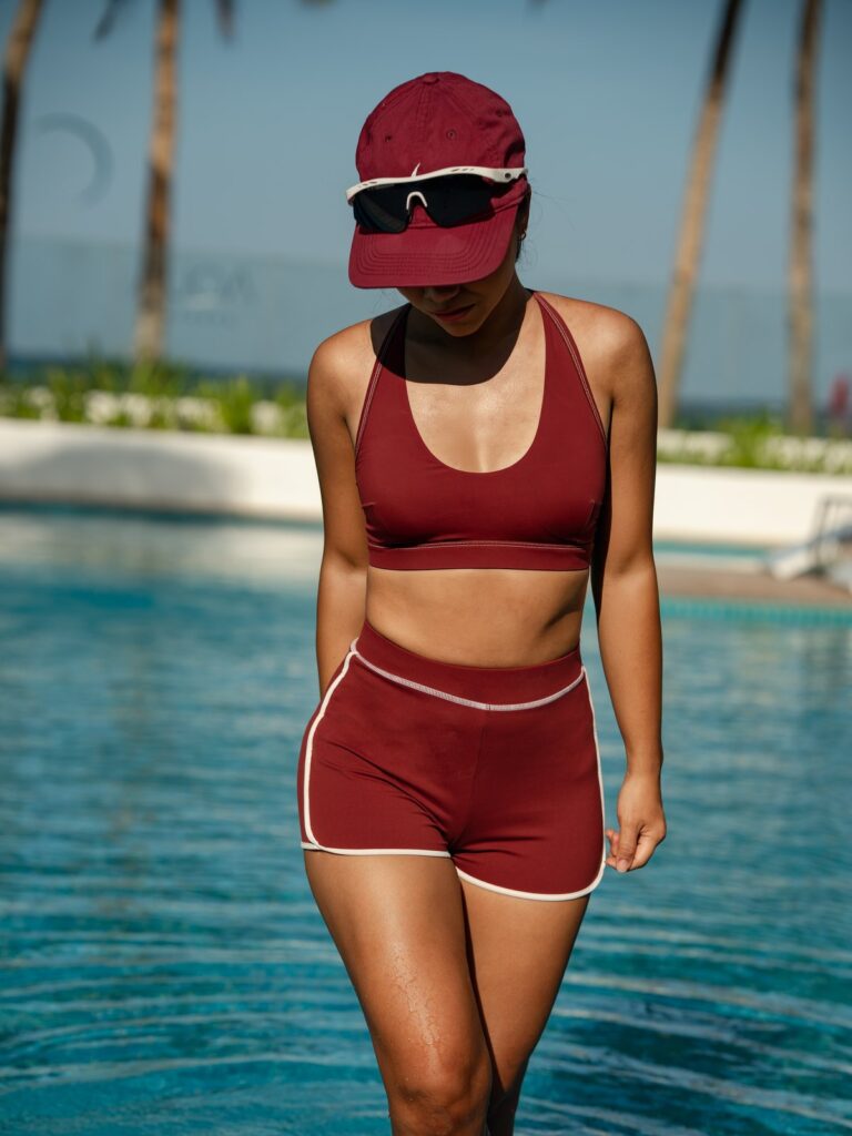 Woman walking out of a pool in the syrah red Cala swim top and boyshort