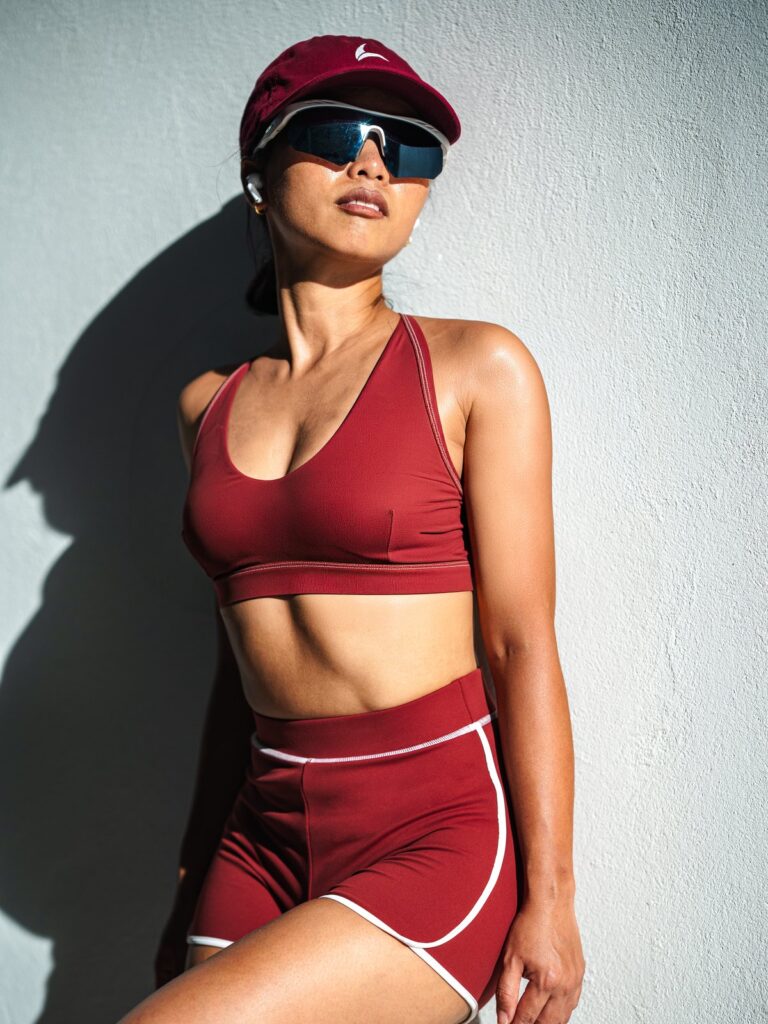 Woman in a cap and sunglasses against a white wall in the Cala top and boyshort