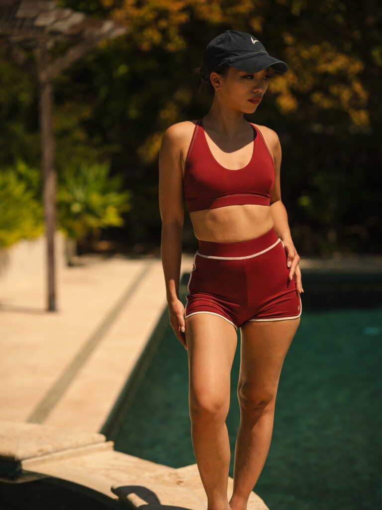 Woman by a pool wearing the syrah red Cala swim top and high-waist boyshort