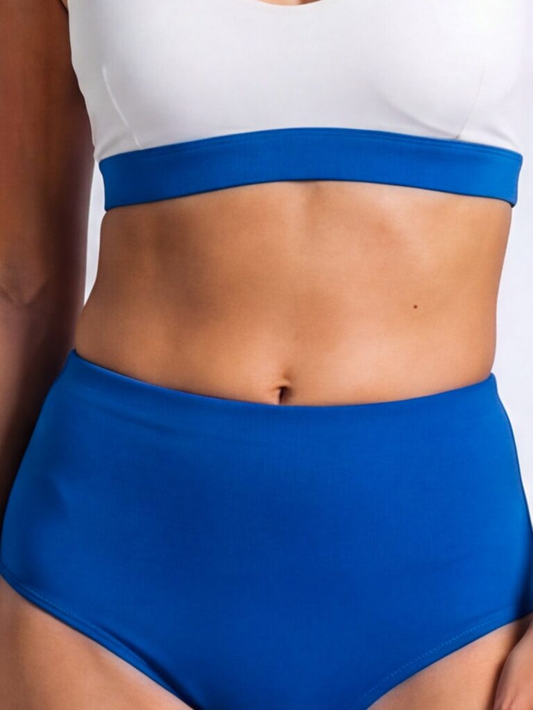 Close-up of the wide royal blue underbust band on the cream white Cala swim top