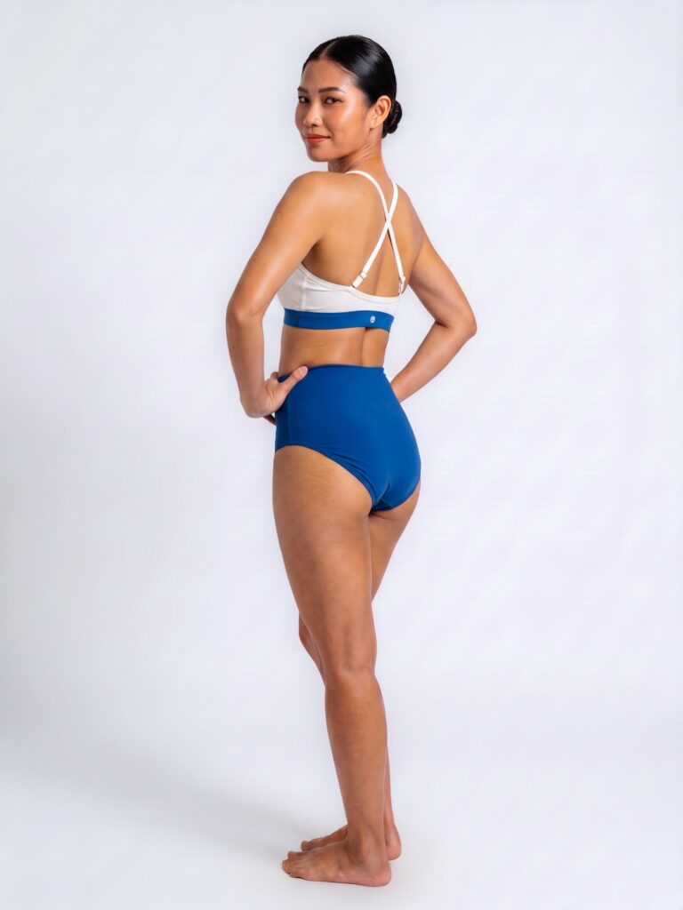 Studio side-back view of the Cala swim top with cross-back straps and royal blue high-waist brief