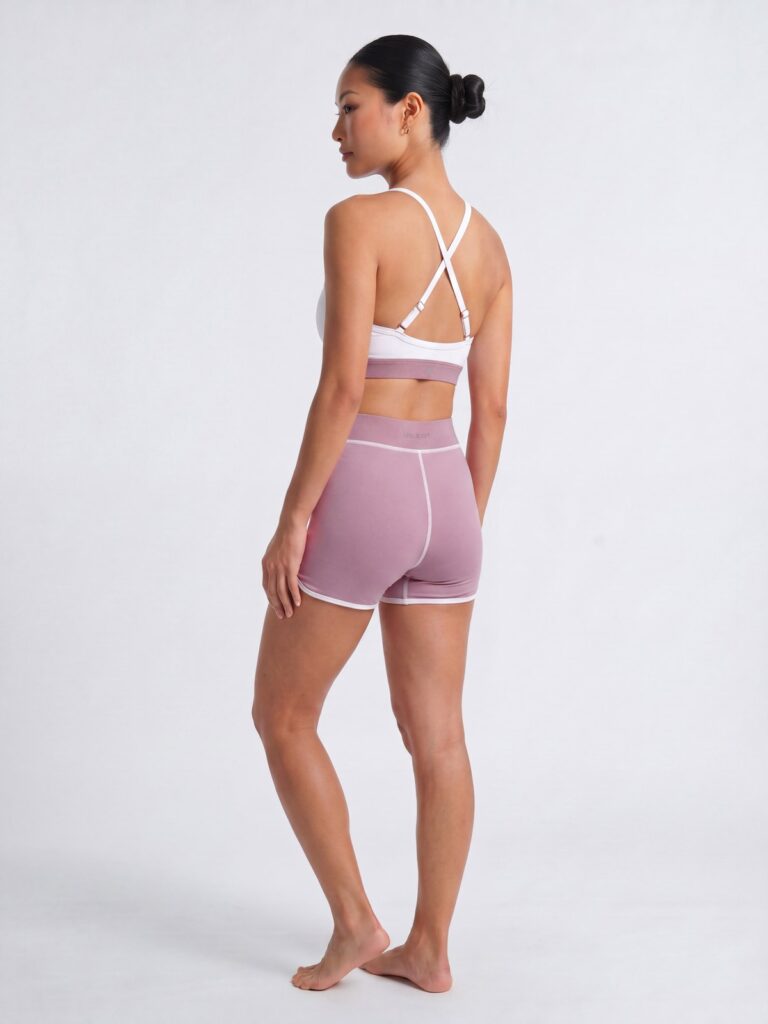 Studio side-back view of the cream white Cala swim top with cross-back straps and wildrose boyshort