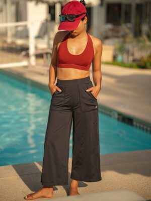 Woman with hands in the pockets of the black wide-leg cropped pull-on pants by a pool