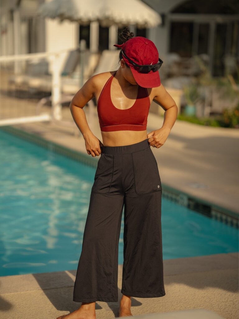 Woman by a resort pool adjusting the waistband of the black wide-leg cropped pants