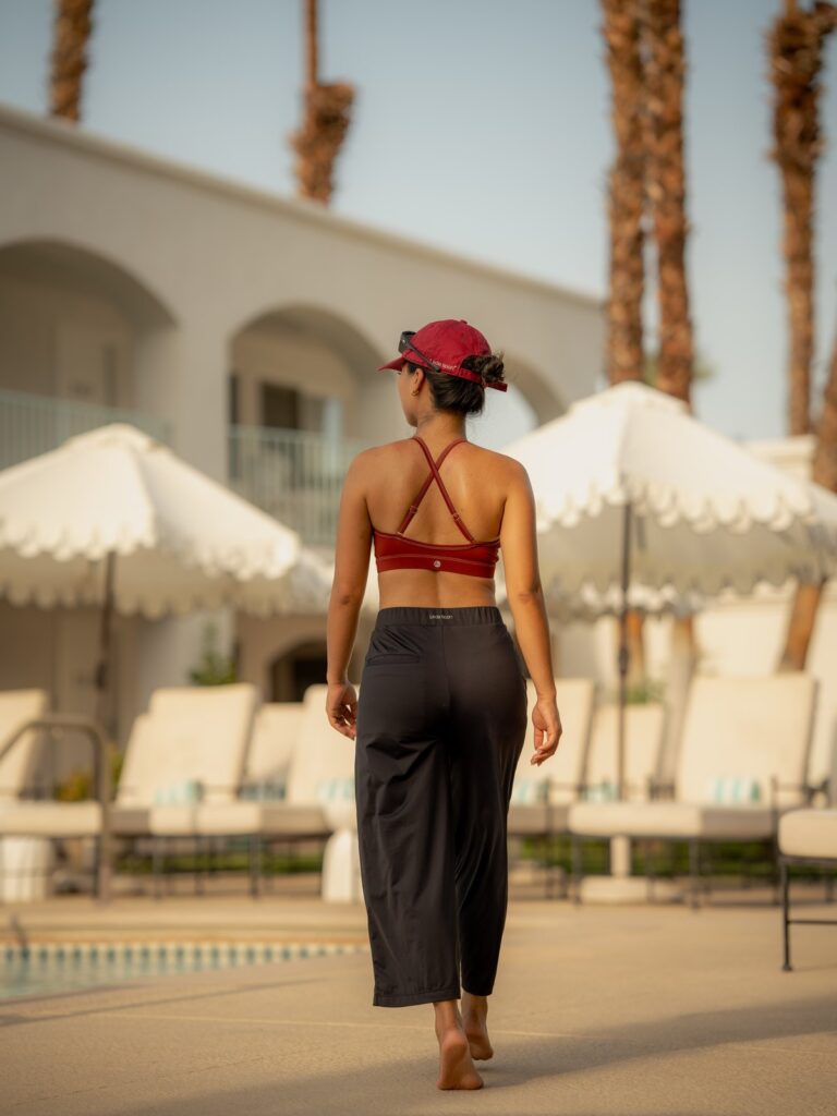 Back view of a woman walking past a resort pool in the black wide-leg cropped pants