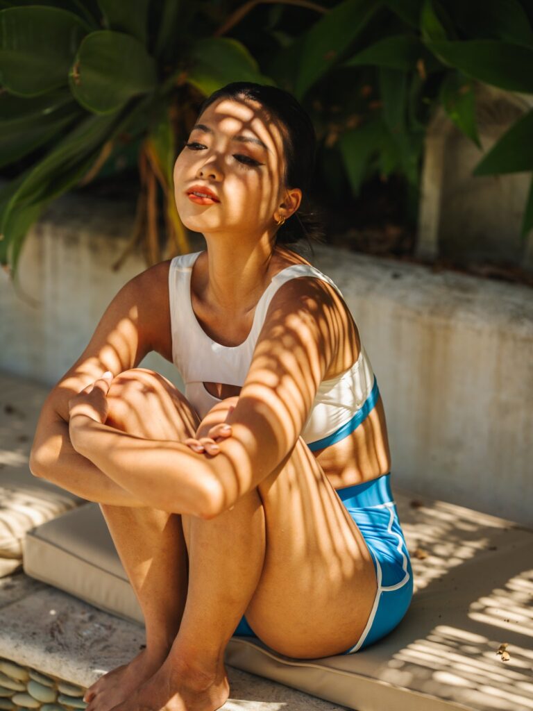 Woman sitting in dappled sunlight in the Siena top and cornflower blue boyshort