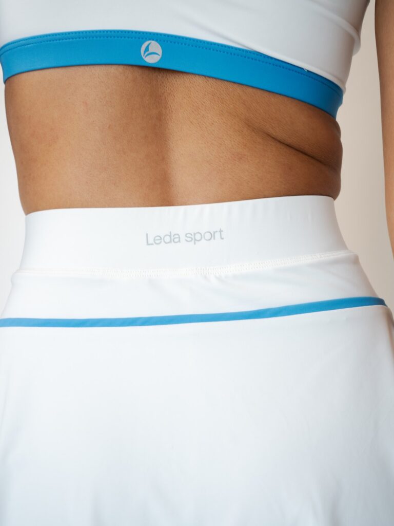 Back close-up of the wide cream white skort waistband with the Leda Sport logo and a blue line