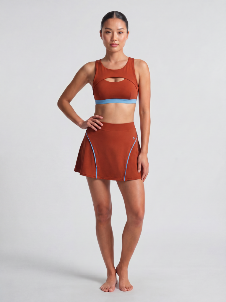 Model wearing the syrah red Siena cutout swim top and high-waist swim skort with light blue seam lines, full-length front view on a white background