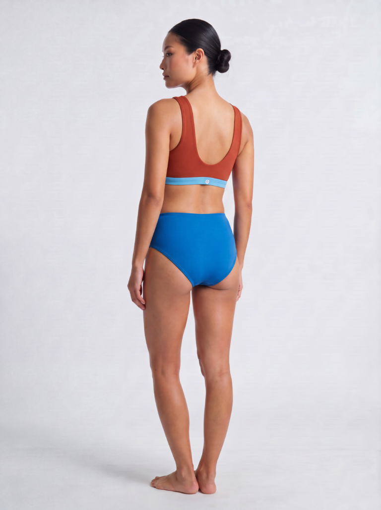 Back view of a model in the royal blue high-waist swim brief and Siena top