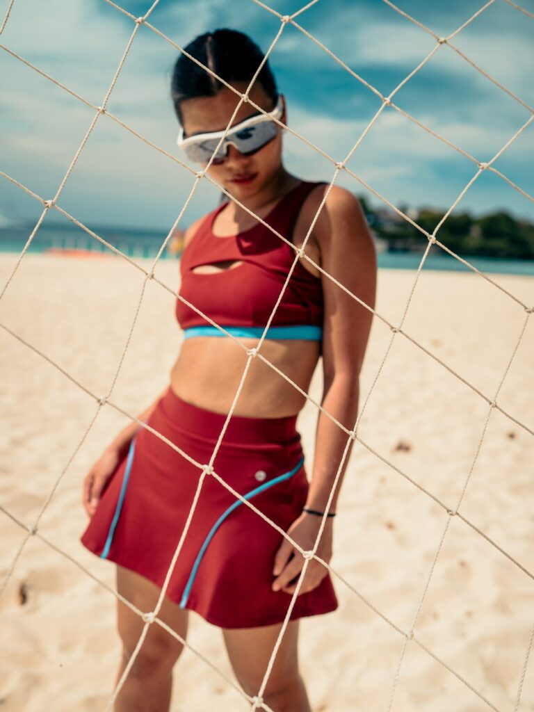Woman on a beach by a volleyball net in the Siena swim top with a curved front cutout