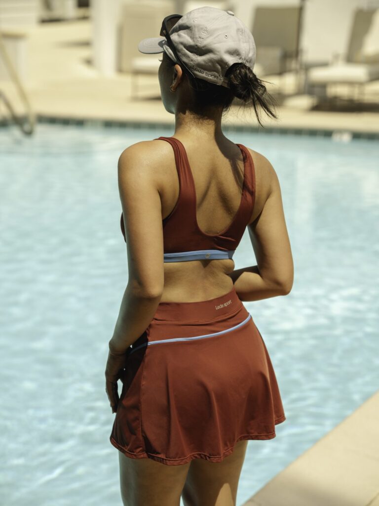 Back view of a woman by a pool in the Siena swim top and skort