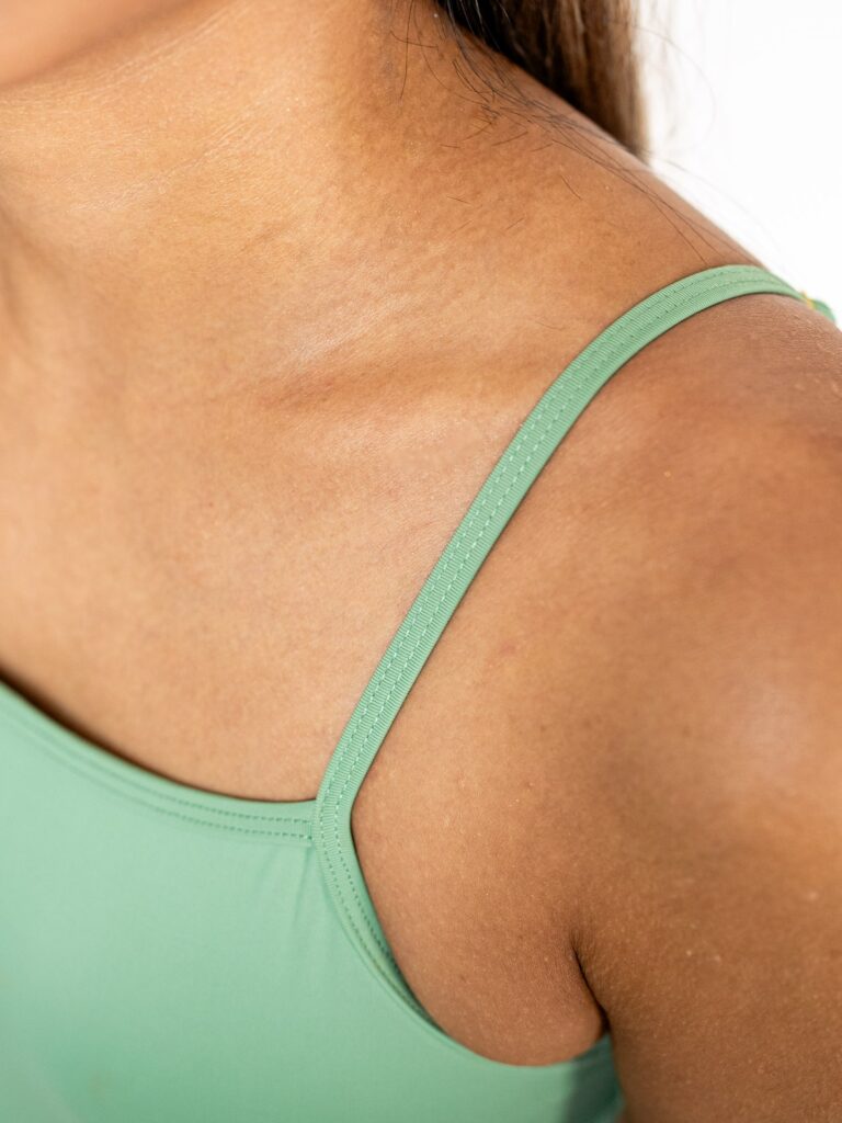 Close-up of a slim adjustable shoulder strap on the matcha green Viva one-piece